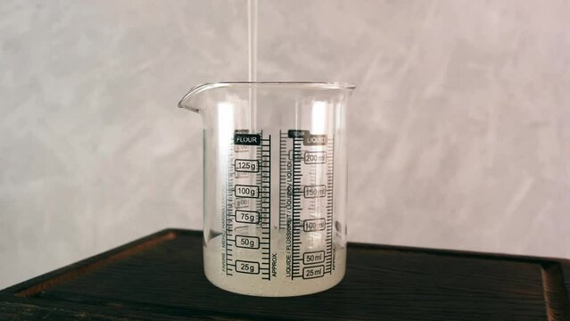 150 ml of Guar gum solution is poured into measuring cup. Guar gum liquid. Food additive E412 is widely used in cosmetic and food industry.