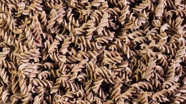Pasta di Lino. Flaxseed gluten free pasta is rich in fiber, iron, B vitamins and Omega-3. Fusilli made from flax and corn flour. Low glycemic index food. Video 4K, counterclockwise rotation.
