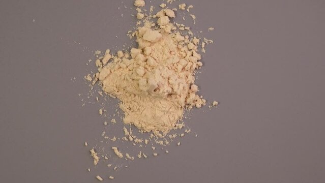 Pile of Soy protein concentrate, isolated from soybean, top view. Pure Soy Protein Isolate powder scattered on grey surface. Food additive, ingredient for fitness cocktail or smoothie.