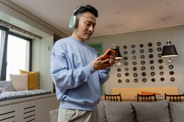 A man with headphones uses a mobile phone at home