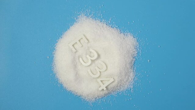 Food additive E 334. Powder. Tartaric acid is a white, crystalline organic acid that occurs naturally in many fruits, most notably in grapes, but also in bananas, tamarinds, and citrus.