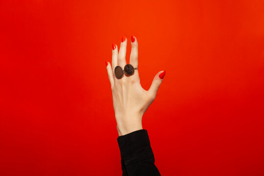 Hand with red nails with rings made of coins