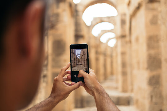 Man taking photos with smartphone in El Djem amphitheater