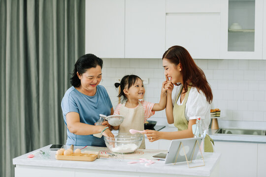 Happy Asian Three Generation Family Baking Together In Kitchen