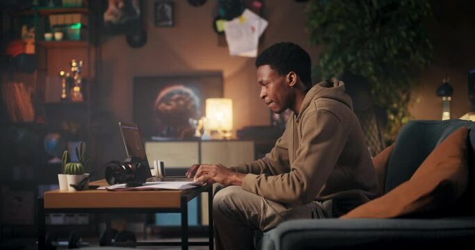 African American remote worker employed in tech-related profession engaged in tasks such as programming, data analysis, or digital marketing. Working remotely allows him to have a flexible schedule.