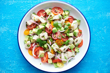 White fish ceviche in a white and blue bowl on a blue background