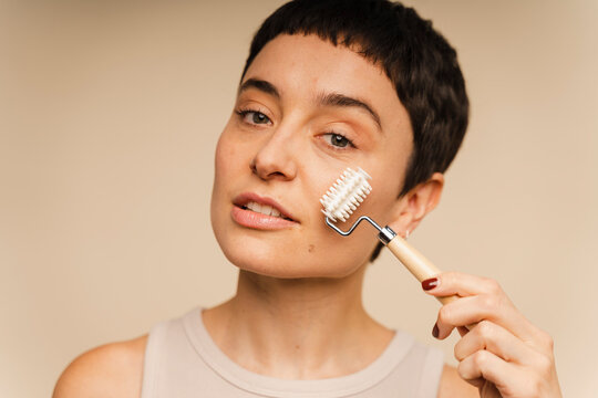 Woman Using Facial Roller During Skin Care