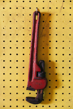 Red Monkey wrench hanging in Garage workshop on Yellow peg board 