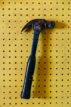 Hardware hammer hanging in Garage workshop on Yellow peg board 