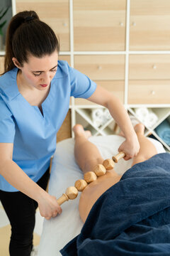 Masseuse using 5-piece roller to massage women's legs.