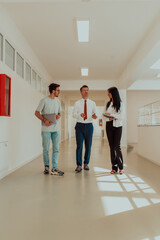 The director conducts a conversation with the secretary and a young programmer in a modern and spacious corridor of a large company, discussing various business topics and projects.