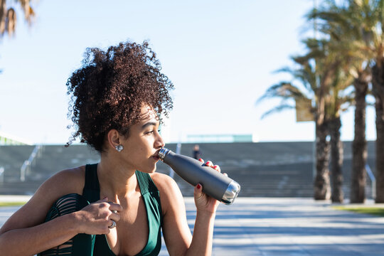 Tired female drinking water after training