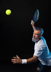 Old padel tennis player with racket in action. Man athlete with paddle tenis racket on court with neon colors. Sport concept. Download a high quality photo for the design of a sports app. - 620723751