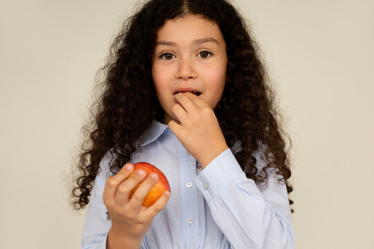 Curly-haired girl loosening her tooth with her hand