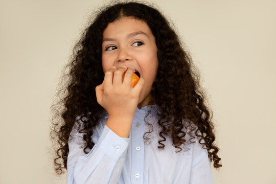 Curly-haired girl takes a big bite out of an apple