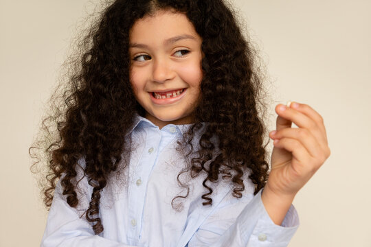 Girl in blue shirt proudly shows her missing tooth
