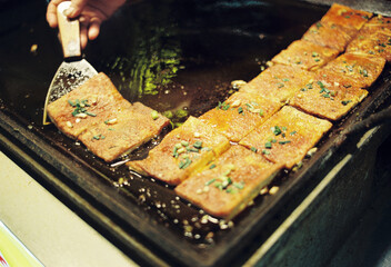 The chef is frying chopped tofu with scallions
