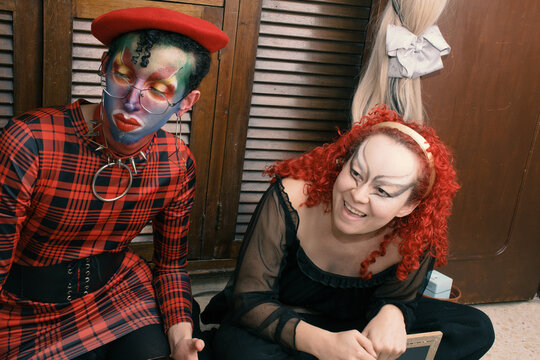 Drag queen helping her friend to do her goth make up 