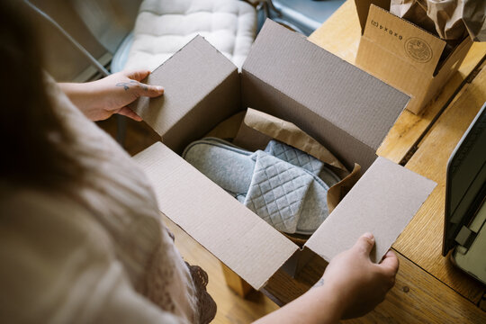 online shopper opening shipping box at home with footwear inside
