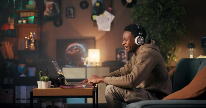 Jamal, the Music Enthusiast: An African American man who enjoys listening to music, smiling, and dancing while sitting on the couch in front of his computer wearing headphones.
