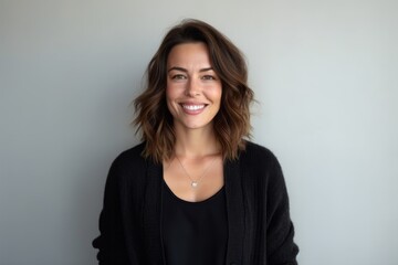 Fototapeta premium Portrait of a smiling young woman looking at camera against grey background