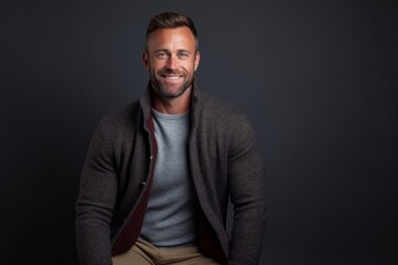 Fototapeta premium Portrait of a handsome man smiling at the camera while standing against black background
