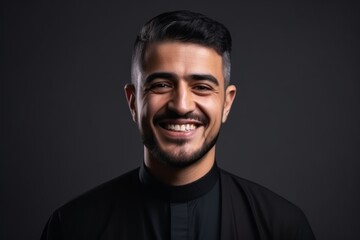 Fototapeta premium Portrait of a smiling young catholic priest on a black background