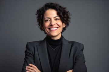 Obraz premium Portrait of a smiling businesswoman in black suit on grey background
