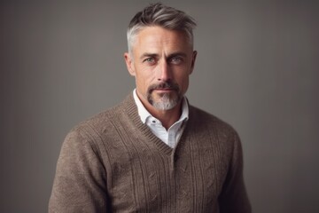 Fototapeta premium Portrait of a handsome mature man with grey hair wearing a brown sweater