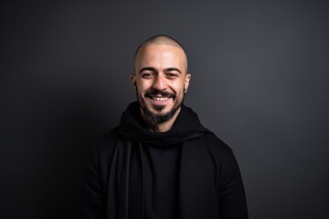 Fototapeta premium Portrait of a smiling bald man in a black hoodie on a black background