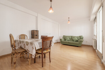 Living room of a house with a wooden dining table with a vinyl tablecloth, wooden chairs, oak...