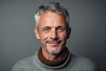 Obraz premium Portrait of a handsome mature man with grey hair wearing a gray sweater.