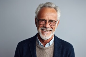 Portrait of a smiling senior man in eyeglasses on grey background