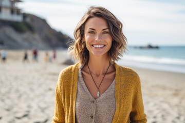 Portrait of beautiful young woman smiling at camera while standing on beach