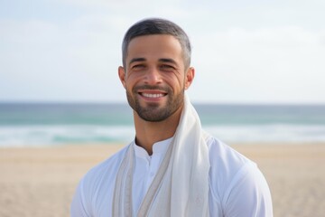 Portrait of a smiling young man with towel standing on the beach