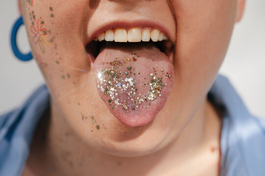 Crop woman showing tongue with glitter
