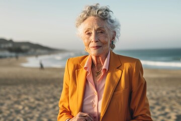 Fototapeta premium Portrait of happy senior woman standing on beach and looking at camera