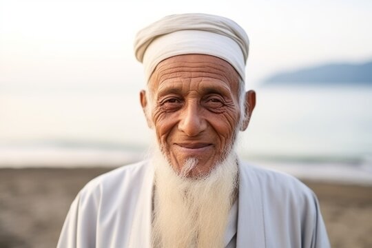 Portrait of happy senior man with white beard and turban on the beach