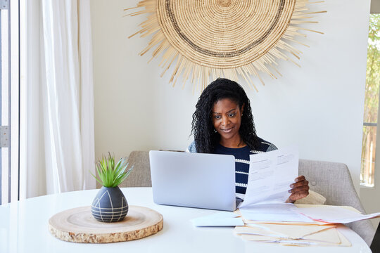 Mature Black woman paying bills online on computer at home