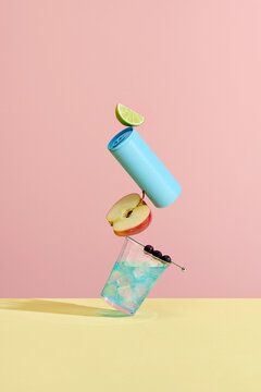 Stack of fresh ripe summer fruits and blue beverage can balancing