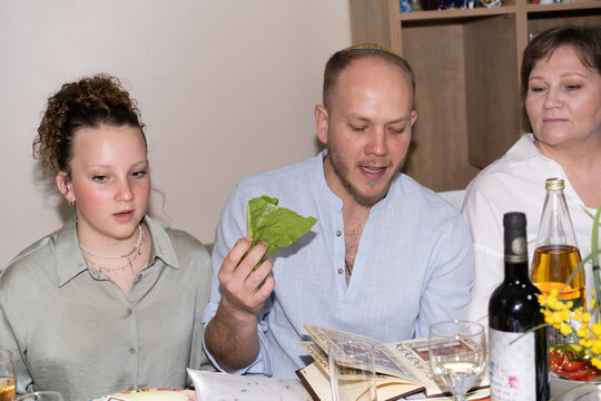 Passover Seder tradition. A man holds lettuce leaves in his hand.