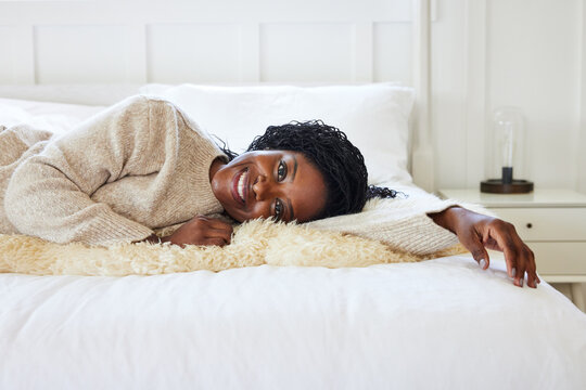 Closeup portrait of happy mature Black woman lying on bed at hom