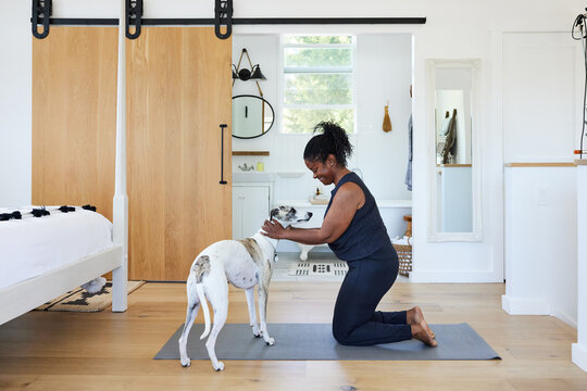 Mature Black woman  getting ready to do yoga in bedroom with pet dog