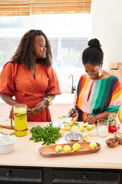 Mature Black women friends cooking healthy meal together in kitchen