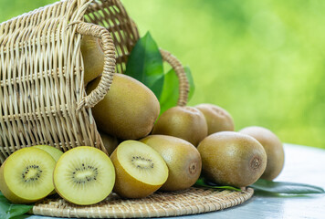 Kiwi fruit in wooden basket over blur greenery background, Yellow kiwi fruit or Chinese gooseberry...