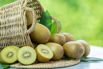 Kiwi fruit in wooden basket over blur greenery background, Yellow kiwi fruit or Chinese gooseberry over green natural Blur background.	
