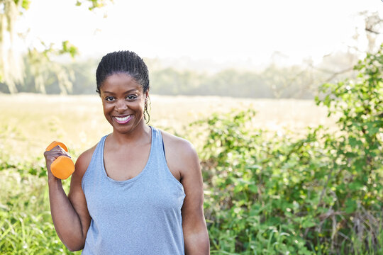 Portrait of Mature Black woman with weights in nature after exercise 