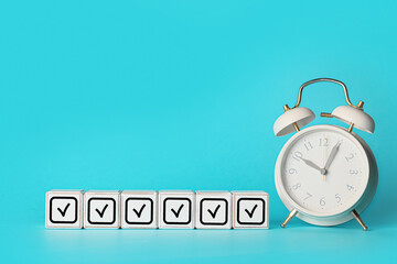 White cubes with check marks and alarm clock on light blue background