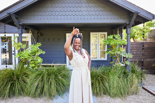 Portrait of happy mature Black woman new home owner holding house