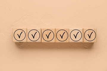 Wooden cubes with check marks on beige background